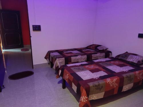 2 bedden in een kamer met paarse muren bij Krishna Kunj Homestay Rishikesh in Rishīkesh