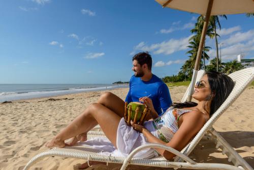 a man and a woman sitting in a chair on the beach at Hardman Praia Hotel in João Pessoa