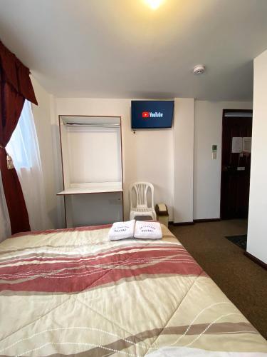 a room with a bed with a chair and a tv at Hostal La Terraza - Roof Terrace Overlooking The North and Historic Centre in Quito