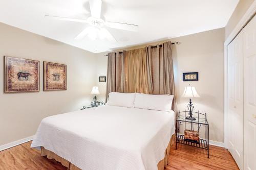 1 dormitorio con cama blanca y ventilador de techo en Three C's 202, en Gulf Shores