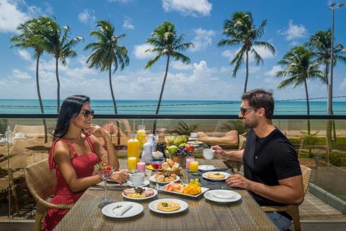 a group of people sitting at a table eating food at Hardman Praia Hotel in João Pessoa