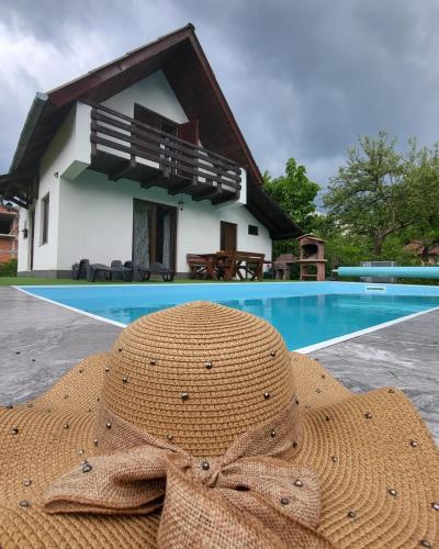 un sombrero de paja sentado frente a una casa en Oaza Mira-vikend kuca sa bazenom, en Pale