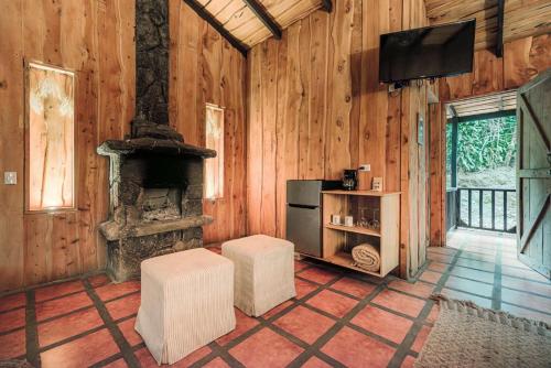 a living room with a stone fireplace and a television at Hotel & Spa Escondite de la Montaña in Sabana Redonda