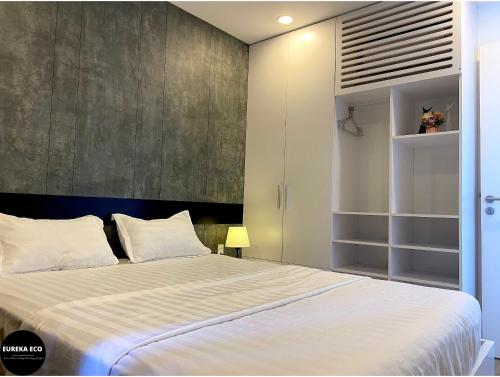 a bedroom with a large white bed and a wall at Eureka Eco in Hue