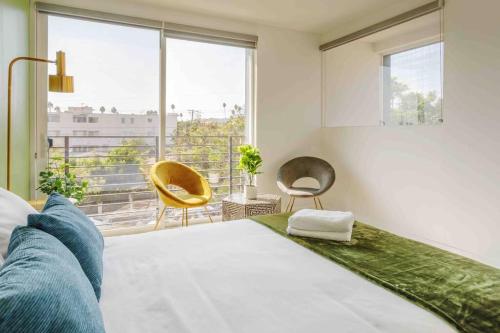 a bedroom with a bed and two chairs and a window at Hollywood Art House with Bright Sunlight in Los Angeles