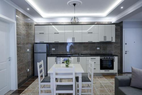 una cucina con armadi bianchi, tavolo e sedie di Fishta apartments Q5 32 a Velipojë