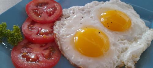 two eggs and tomatoes on a blue plate at THE SANCTUARY LODGE in Foulpointe