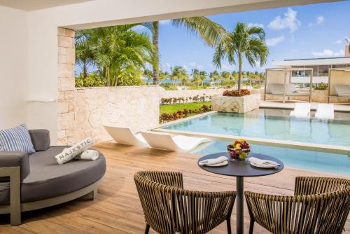 a living room with a table and chairs and a pool at Majestic Elegance Costa Mujeres - All Inclusive in Cancún