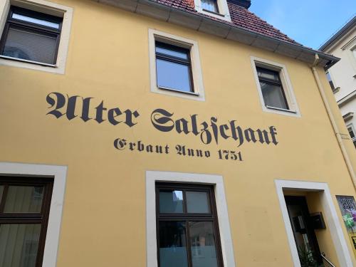 un bâtiment jaune avec un panneau sur lequel figure un panneau dans l'établissement Stilvolle Altbauwohnung im Zentrum von Bad Schandau, à Bad Schandau
