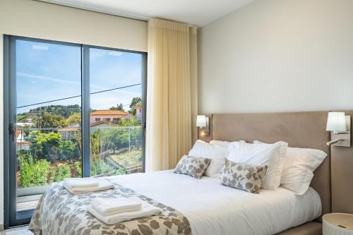 um quarto com uma cama e uma grande janela em Belle Maison I by Madeira Sun Travel em Funchal