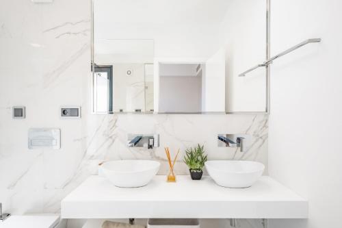 2 Waschbecken in einem weißen Badezimmer mit Marmorwänden in der Unterkunft Belle Maison I by Madeira Sun Travel in Funchal