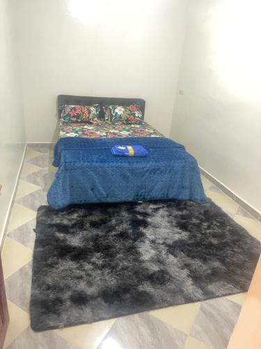 Una cama con una manta azul y una alfombra negra en شقق المستقبل المفروشة, en Laayoune