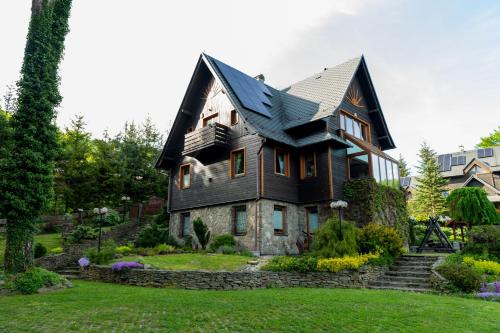 a house with a black roof on a green yard at Family Relax & Willa Widok in Szczyrk