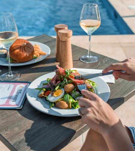 a person cutting a plate of food on a table with wine glasses at Grand Windsock Bonaire in Kralendijk