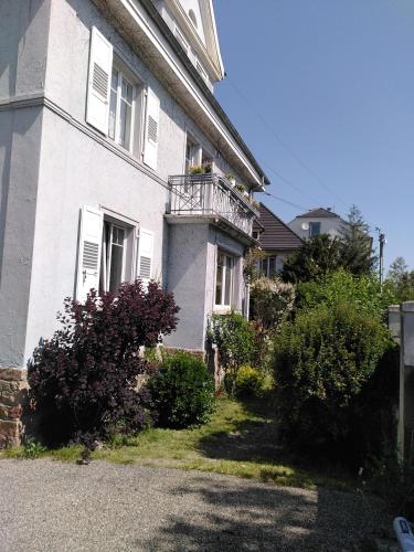 Cette maison blanche dispose d'un balcon et de quelques buissons. dans l'établissement La chambre de la maison bleue, à Colmar