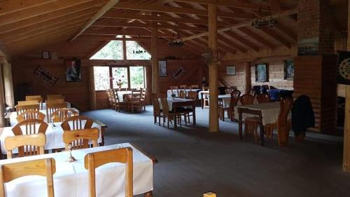 une salle à manger avec des tables blanches et des chaises en bois dans l'établissement Mulliri, à Peje