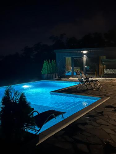 uma piscina à noite com duas cadeiras ao lado em Rinari Spa House em Barič