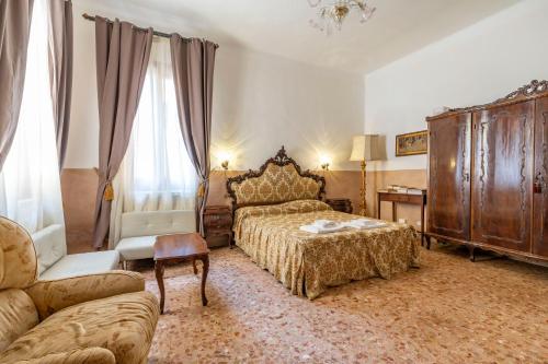 Queen House Venezia في البندقية: غرفة نوم بسرير وكرسي وأريكة