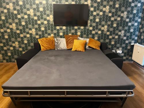 a black couch with pillows and a tv on a wall at Apartment Spa and Fontain Poděbrady in Poděbrady