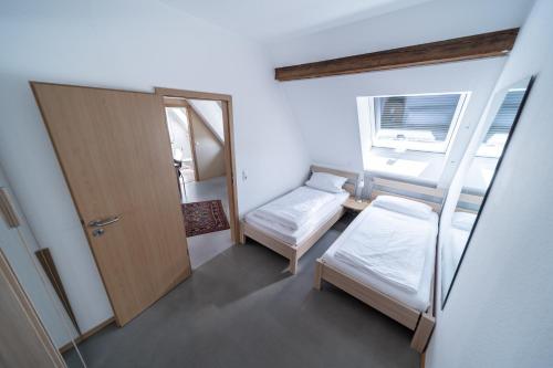 a small room with two beds and a door at Milchhof Apartments Aschaffenburg in Aschaffenburg