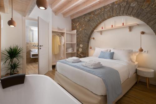 um quarto com uma grande cama branca e uma parede de pedra em Cedrus Blue em Simi