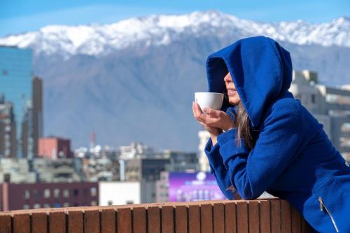 una mujer sentada en una cornisa sosteniendo una taza de café en Four Points by Sheraton Santiago, en Santiago