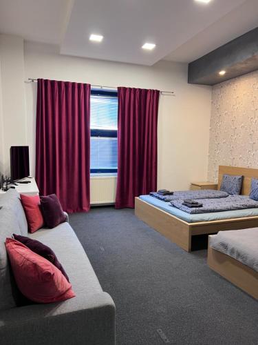 a bedroom with two beds and a window with red curtains at Downtown Apartments in Pilsen