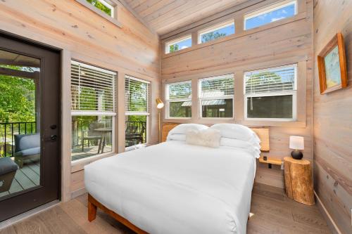 a bedroom in a tiny house with a bed and windows at Asheville River Cabins in Arden