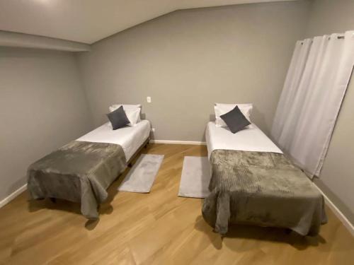 2 Betten in einem Zimmer mit Holzböden in der Unterkunft Casa Sublime na Serra in Campos do Jordão