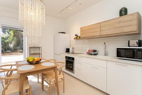 a kitchen with white cabinets and a table with a bowl of fruit at Carmel Boutique - City Oasis in Haifa