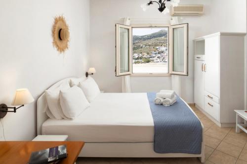 a white bedroom with a bed and a window at Almar Apartments in Batsi