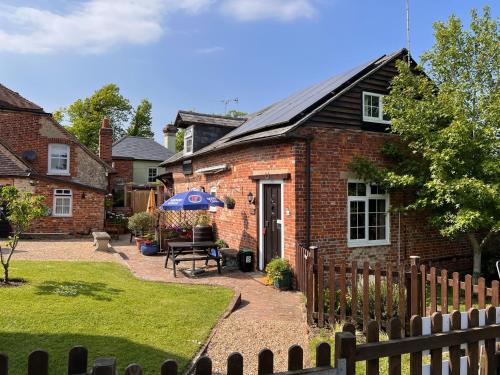 une maison en briques avec une table et un parasol dans l'établissement Hunston Mill Self Catering Dog Friendly, à Chichester