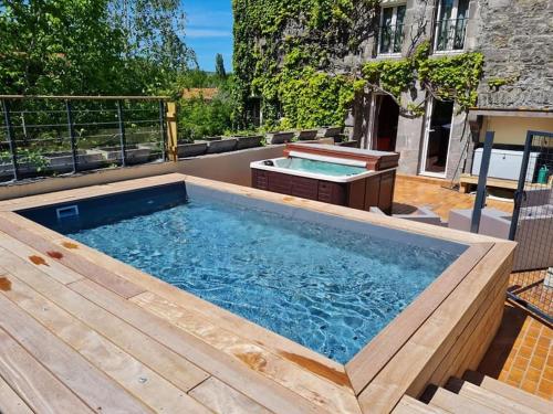 une grande piscine avec une terrasse en bois et un bain à remous dans l'établissement Le Moulin des Poètes, à Malauzat