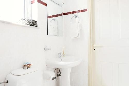 a white bathroom with a sink and a toilet at Mediterranea Apartments in Kato Daratso