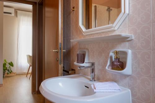 La salle de bains est pourvue d'un lavabo blanc et d'un miroir. dans l'établissement Maison D'Or, à Trieste