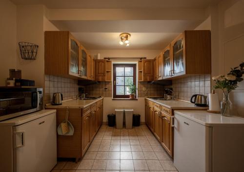a kitchen with wooden cabinets and a tile floor at Pension Cirf in Strážné