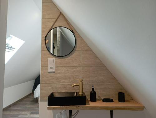 une salle de bain avec un lavabo et un miroir dans l'établissement Gîte avec son bain nordique privatif au feu de bois, à Pleubian