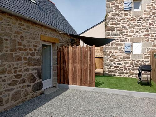 ein Steingebäude mit einem Holztor und einem schwarzen Regenschirm in der Unterkunft Gîte avec son bain nordique privatif au feu de bois in Pleubian