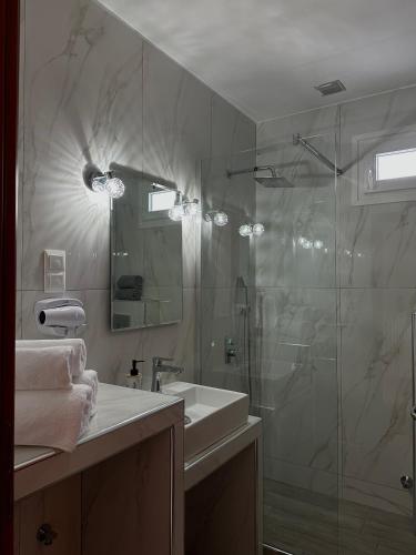 a bathroom with a glass shower and a sink at To Spiti in Keramoti