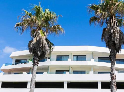 雪梨的住宿－Bondi Beach Waves Beachfront Apartment，一座白色的建筑,前面有棕榈树
