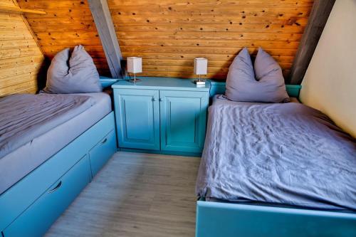 Duas camas num quarto com mobiliário azul e paredes de madeira em Chalet Alba em Lichtenberg