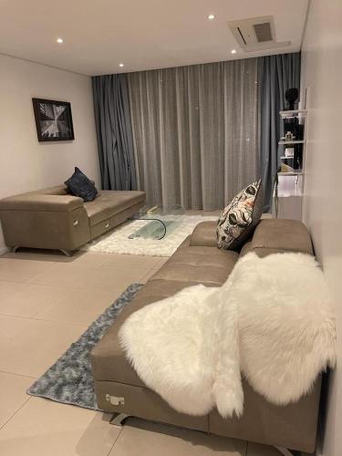 a living room with a couch with white fur at Zimbali Suites 212, Zimbali Estate in Ballito
