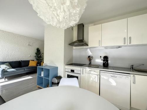 une cuisine avec des armoires blanches et une table blanche dans l'établissement Appartement aux portes des Gorges du Tarn, à Ispagnac