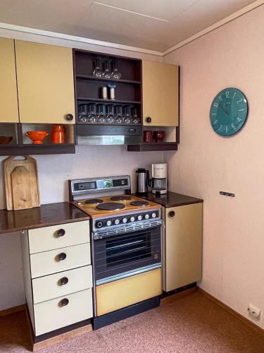 a kitchen with a stove and a clock on the wall at Havgaarden, apt 1 in Stapnes