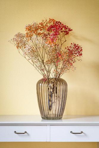 a vase with flowers in it sitting on a dresser at Havgaarden, apt 1 in Stapnes