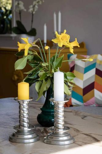 two candles and a vase with flowers on a table at Havgaarden, apt 1 in Stapnes