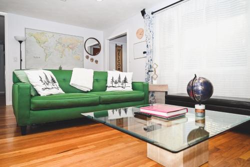a living room with a green couch and a glass table at Cozy Oasis: Luxury & Modern Apartment By Revere Beach in Revere
