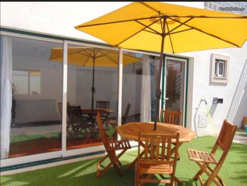 a table and chairs with umbrellas on a patio at Casinha Rés do Chão na Nazaré com Quintal e Barbecue in Nazaré