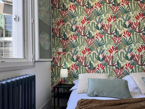 a bedroom with a bed with a floral wallpaper at Hotel TULTY in Tours