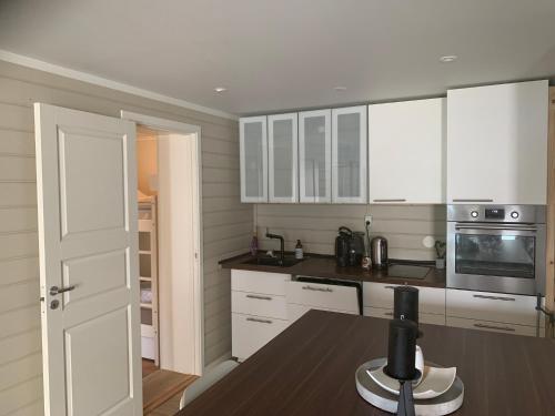 uma cozinha com armários brancos e uma mesa de madeira em Solvik #apartment #Loen em Loen